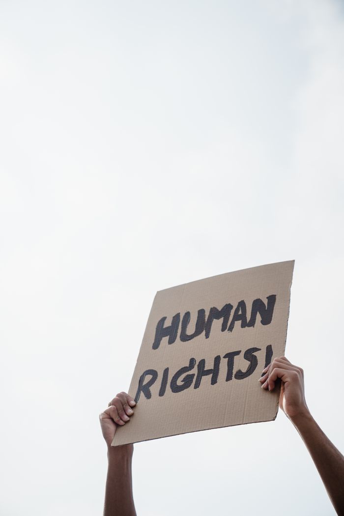 A close-up of a human rights protest sign held up against the sky.
